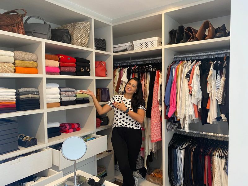 Esther Zayat, professional organizer, smiling in an organized walk-in closet