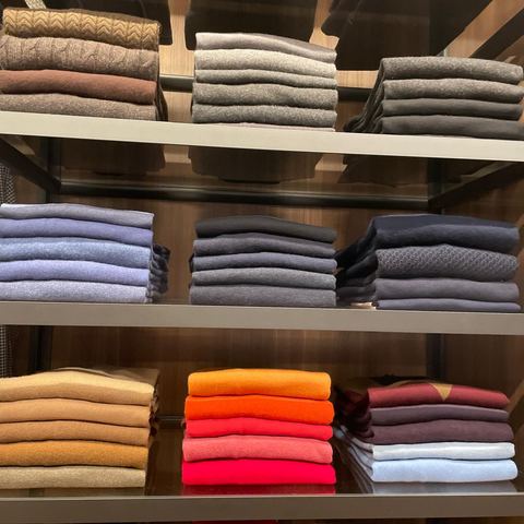 Folded sweaters arranged by color on glass shelves