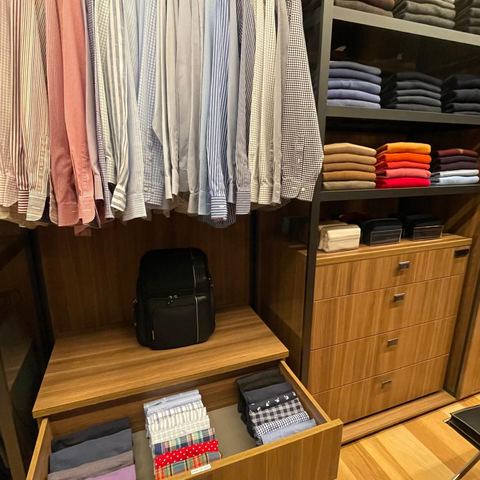 Striped dress shirts above an open drawer of neatly folded clothes