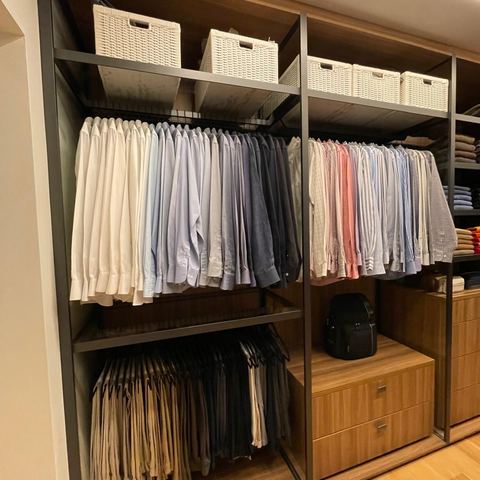 Built-in wardrobe with shirts on hangers and woven storage baskets above